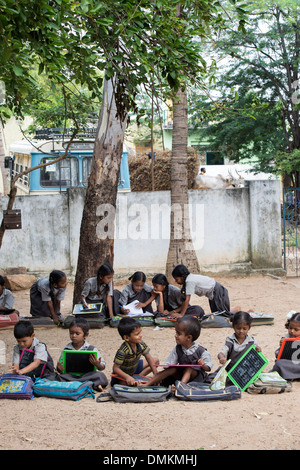 Rurale villaggio indiano la scuola dei bambini in una classe esterna scrivendo su un chalk compresse. Andhra Pradesh, India Foto Stock