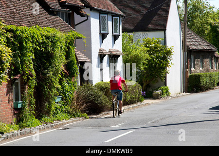 Ciclista nella strada principale del villaggio di Bramber, West Sussex, in Inghilterra, Regno Unito. Foto Stock
