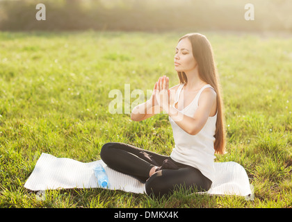 Donna attraente le pratiche yoga in natura. Lotus pongono a occhi chiusi Foto Stock