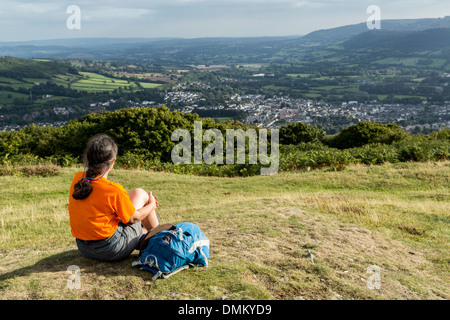 Donna seduta su di una collina che si affaccia sulla città di Abergavenny, Wales, Regno Unito Foto Stock