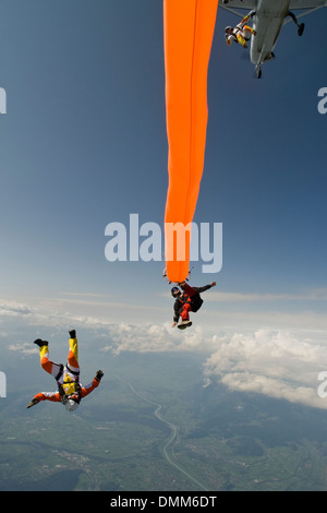 Paracadutista con colorati tubo di aria è immersioni nel blu del cielo. Alcuni amici del ponticello sono battenti intorno al tubo di aria e divertirsi. Foto Stock