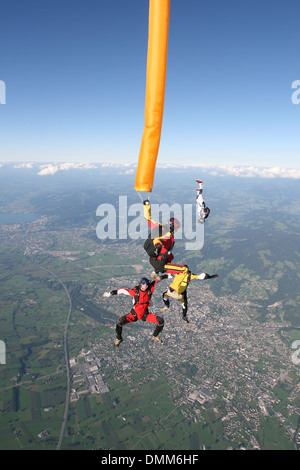 Paracadutista con colorati tubo di aria è immersioni nel blu del cielo. Alcuni amici del ponticello sono battenti intorno al tubo di aria e divertirsi. Foto Stock