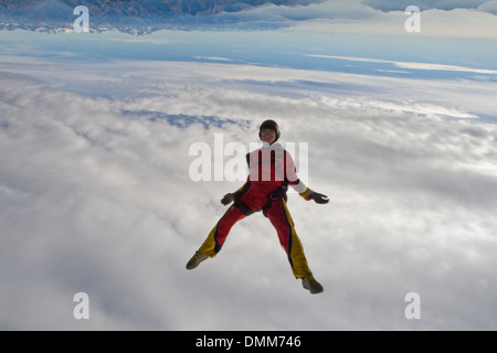 Questo paracadutista donna è caduta libera in una testa abbassata nel cielo nuvoloso. In tal modo il mondo è capovolto. Foto Stock