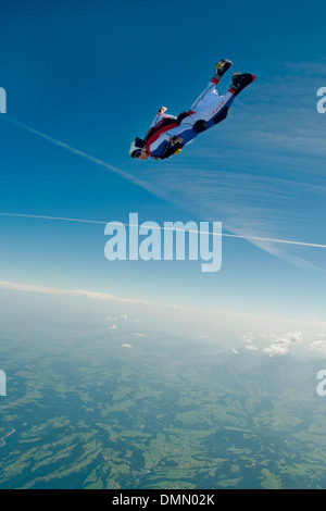 Paracadutista è volare nella sua Wingsuit e subacquea è giù dal cielo blu verso terra con velocità alta. Foto Stock