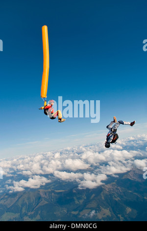 Paracadutista con colorati tubo di aria è immersioni nel blu del cielo. Un amico del ponticello è volare intorno al tubo di aria ed ha divertimento. Foto Stock