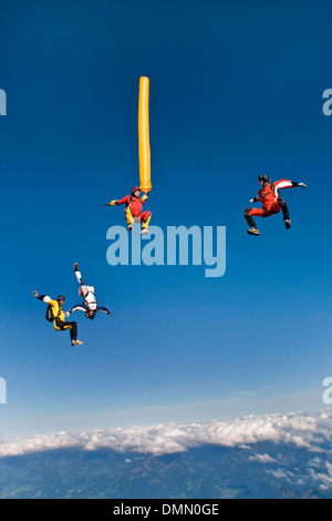 Paracadutista con colorati tubo di aria è immersioni nel blu del cielo. Alcuni amici del ponticello sono battenti intorno al tubo di aria e divertirsi. Foto Stock