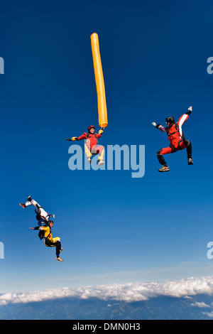 Paracadutista con colorati tubo di aria è immersioni nel blu del cielo. Alcuni amici del ponticello sono battenti intorno al tubo di aria e divertirsi. Foto Stock