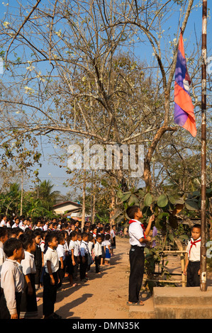 Vista verticale della scuola bambini salutando e cantando insieme durante la loro bandiera il sollevamento ad una scuola in Laos. Foto Stock