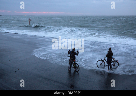 Paesi Bassi, Vlissingen, giovane sulle biciclette di bagnare i piedi durante la tempesta Foto Stock