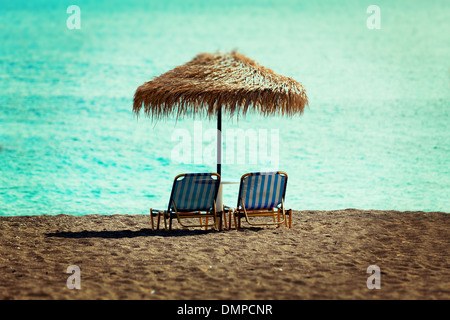Spiaggia di lettini e ombrelloni di paglia sulla spiaggia Foto Stock