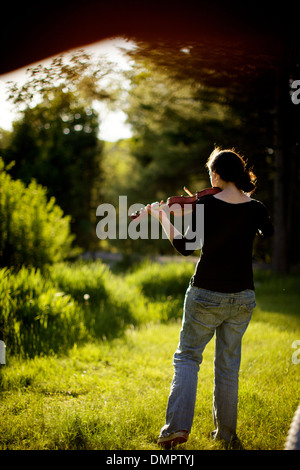 La luce del sole lambisce la forma di un giovane brunette fiddle player, sperimentando con variazioni di Bach nel sole del pomeriggio. Foto Stock