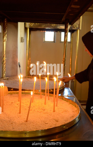 Nun accendendo candele presso il monastero di San Gerasimus, Cefalonia, Grecia Foto Stock