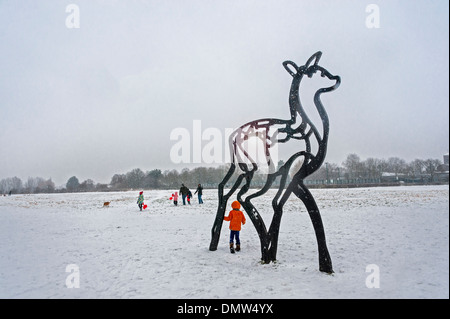 Famiglia nella neve con il gigante scultura di cervo. Foto Stock