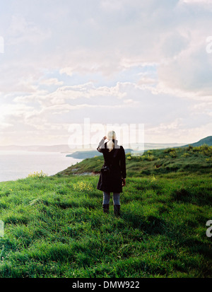 Una donna che guarda lungo il litorale di insenature e scogliere. Foto Stock