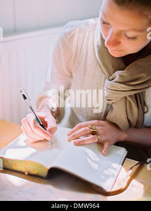 Una donna con un pennarello colorato disegno su una pagina vuota di un diario. Foto Stock