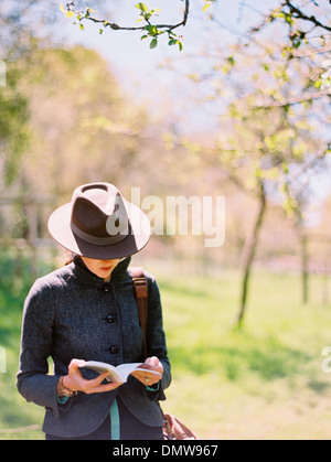Una donna in un cappello la lettura di un libro. Foto Stock