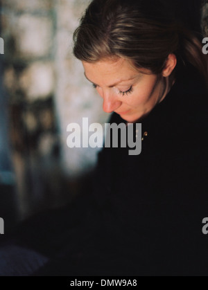 Una donna che indossa un mantello nero guardando verso il basso in un umore pensieroso. Foto Stock