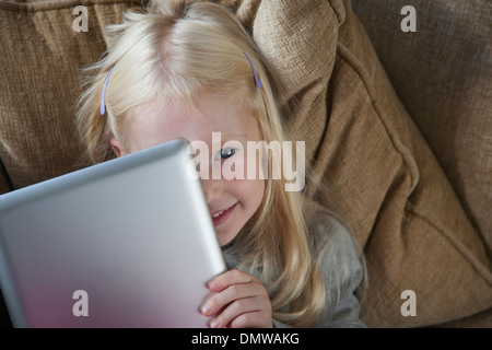 Una giovane ragazza in possesso di un computer portatile di argento nella parte anteriore del suo volto. Foto Stock