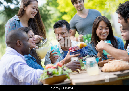 Adulti e bambini intorno a un tavolo in un giardino. Foto Stock