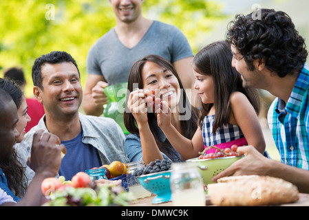 Adulti e bambini intorno a un tavolo in un giardino. Foto Stock