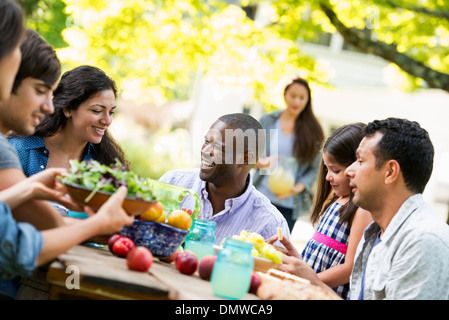 Adulti e bambini intorno a un tavolo in un giardino. Foto Stock