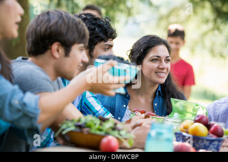Adulti e bambini intorno a un tavolo a una festa in giardino. Foto Stock