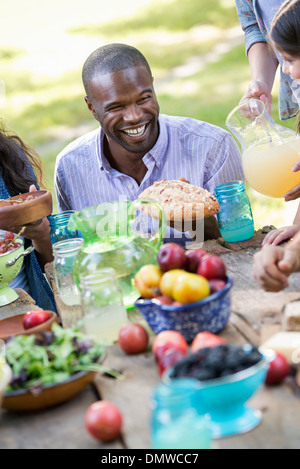 Adulti e bambini intorno a un tavolo a una festa in giardino. Foto Stock