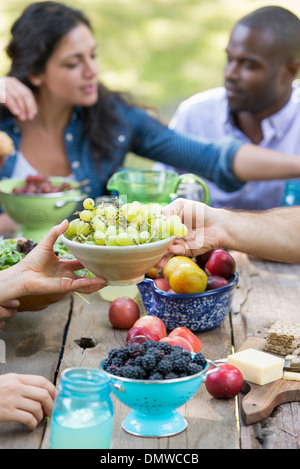 Adulti e bambini intorno a un tavolo a una festa in giardino. Foto Stock