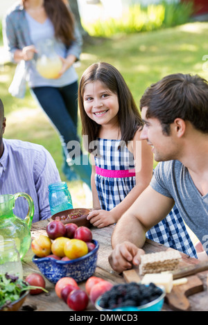 Adulti e bambini intorno a un tavolo a una festa in giardino. Foto Stock