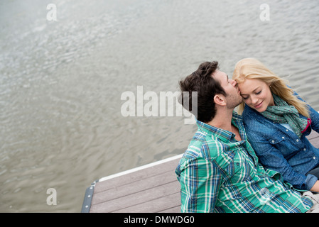 Un uomo e una donna seduta su un molo da un lago. Foto Stock