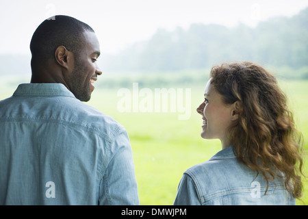 Un giovane uomo e donna un paio di fianco a fianco. Guardando ogni o. Foto Stock