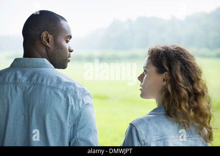 Un giovane uomo e donna un paio di fianco a fianco. Guardando ogni o. Foto Stock