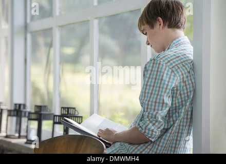 Un giovane persona seduta a leggere un libro. Foto Stock