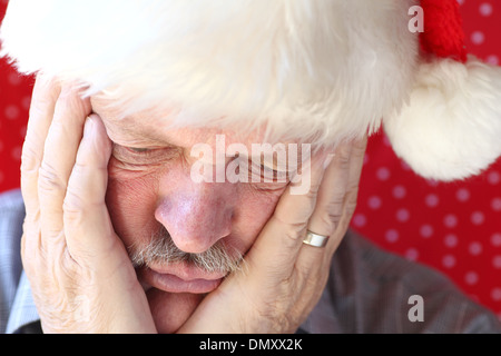 Senior uomo faccia tiene in mano e guarda verso il basso Foto Stock