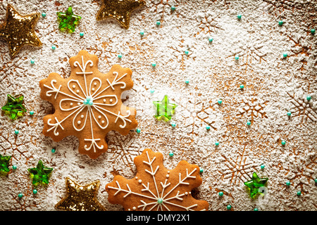 Gingerbreads natale fiocchi di neve su sfondo costituito ​​of zucchero a velo su un tavolo di legno. Vista superiore Foto Stock