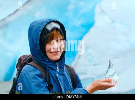 Ritratto di donna felice con un pezzo di ghiaccio in mano sul ghiacciaio Nigardsbreen sfondo (Norvegia) Foto Stock