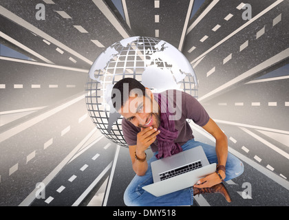 Immagine composita di pensosa uomo seduto sul pavimento con il laptop e sorridente in telecamera Foto Stock