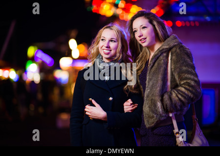 Due ragazze adolescenti amici giovani donne divertirsi presso il parco di divertimenti della fiera di notte REGNO UNITO Foto Stock