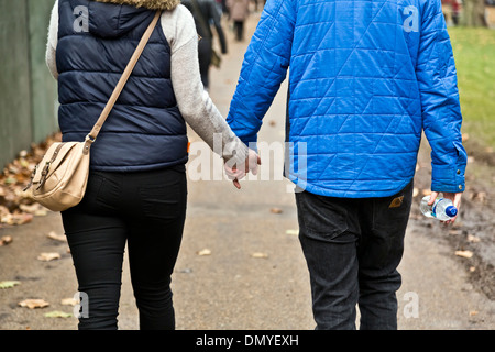 Un giovane tenendo le mani a piedi in Hyde Park di Londra, Inghilterra Foto Stock