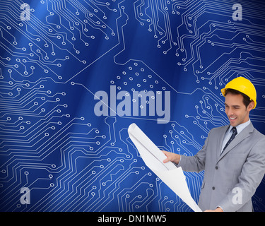 Immagine composita di sorridere architetto con elmetto guardando i piani Foto Stock