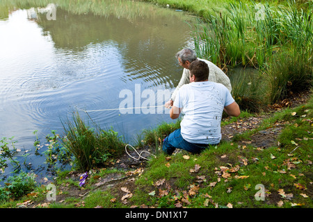 Il dragaggio di rifiuti al di fuori di un laghetto Foto Stock