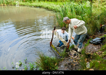 Rimozione di rifiuti da un laghetto Foto Stock