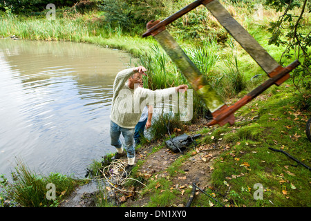 Rimozione di rifiuti da un laghetto Foto Stock