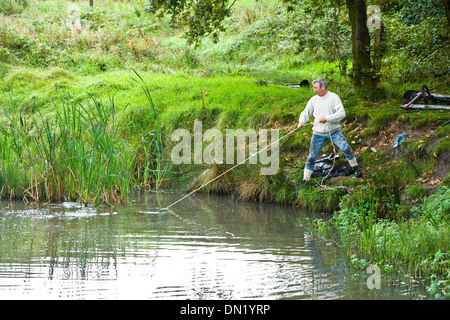 Il dragaggio di rifiuti al di fuori di un laghetto Foto Stock