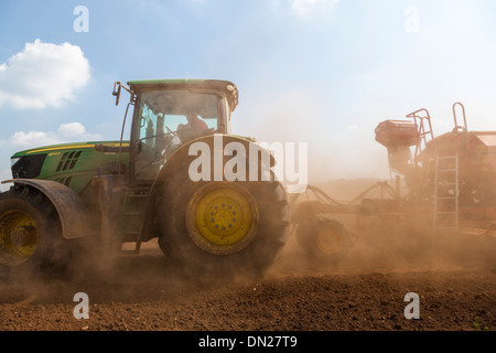 Terreno polveroso vola da ruote e attrezzature come un trattore trapani seme in un campo. Foto Stock