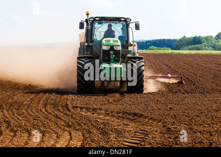 Terreno polveroso vola da ruote e attrezzature come un trattore trapani seme in un campo. Foto Stock