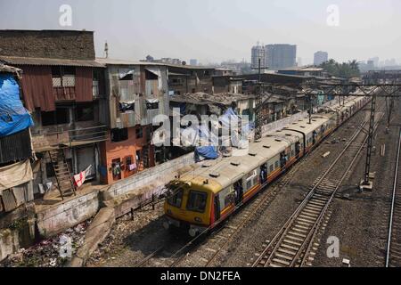 Mumbai, India. Xviii Dicembre, 2013. Un treno passa dal delle baraccopoli di Mumbai, India, Dic 18, 2013. In corrispondenza dell'altro lato dell India finanziaria e centro economico, Mumbai, vi si trova una delle maggiori aree povere del paese. I residenti vivono in squallide, congestionati camere e craps sono visibile dappertutto. Ma la vita in Mumbai della baraccopoli zona non è tutto circa la povertà e il pessimismo, alcune persone hanno iniziato ad aprire negozi, di inviare i loro bambini a scuola e di fare business. Foto Stock