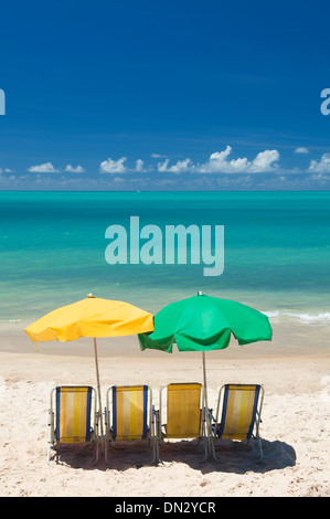 Spiaggia Tropicale scena con quattro sedie a sdraio e due ombrelli in Nordeste brasile Foto Stock