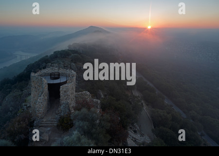 Sunrise oltre il Castillo de Monfrague con laminazione nebbia sulle colline Foto Stock