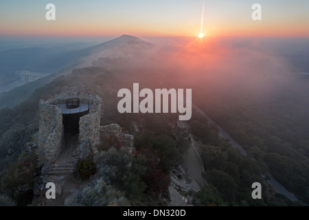 Sunrise oltre il Castillo de Monfrague con laminazione nebbia sulle colline Foto Stock